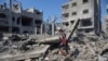 Warga Palestina berdiri di dekat bangunan yang hancur akibat serangan udara Israel di Deir al-Balah, selatan Jalur Gaza, Sabtu, 14 Oktober 2023. (AP /Hatem Moussa)