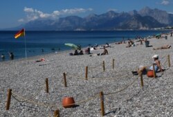 A man sits in an area marked by cordons of ropes and wooden stakes to enforce social distancing measures on the Konyaalti beach, amid the COVID-19 outbreak, in the southern resort city of Antalya, Turkey, June 19, 2020.