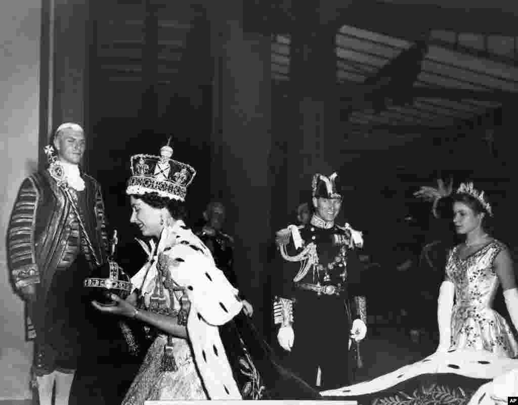 Ratu Inggris Elizabeth II mengenakan Mahkota Kerajaan berhiaskan berlian dan membawa Orb dan Tongkat Kerajaan dengan Salib, meninggalkan Westminster Abbey, London, pada akhir upacara penobatannya sebagai Ratu Inggris, 2 Juni 1953. 