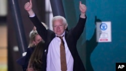 Pendiri WikiLeaks Julian Assange mengangkat kedua tangan, setelah mendarat sebagai orang bebas di pangkalan udara RAAF Fairbairn di Canberra, Australia, Rabu 26 Juni 2024.
