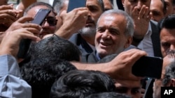 Kandidat reformis dalam pemilihan presiden Iran Masoud Pezeshkian disambut oleh para pendukungnya saat ia tiba untuk memberikan suara di tempat pemungutan suara di Shahr-e-Qods dekat Teheran, Iran, 5 Juli 2024. (Foto: AP)
