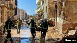 Anggota tim penyelamat dari tentara Mesir membawa mayat korban melewati lumpur di antara bangunan yang hancur akibat badai dan hujan lebat di Derna, Libya, 13 September 2023. (REUTERS/Ahmed Elumami)