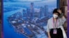 Seorang perempuan mengenakan masker saat berada di sebuah area di Shanghai, pada 6 Juli 2023. (Foto: AP/Ng Han Guan)