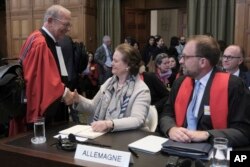 Tania von Uslar-Gleichen, penasihat hukum Jerman dan Direktur Jenderal Urusan Hukum Kementerian Luar Negeri Jerman (tengah), berjabat tangan dengan Alain Pellet (kiri), pengacara yang mewakili Nikaragua di Den Haag, Belanda, Senin, 8 April 2024. (AP/Postingan Patrick)