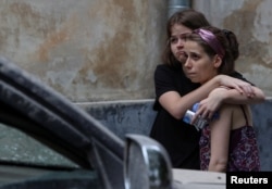 Local residents react at a site of a residential building hit by a Russian missile strike, amid Russia's attack on Ukraine, in Lviv, Ukraine, July 6, 2023.