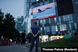 Seorang pria menonton siaran berita CCTV yang menunjukkan jet tempur di dekat Taiwan oleh Komando Teater Timur Tentara Pembebasan Rakyat China (PLA), di sebuah pusat perbelanjaan di Beijing, China, 3 Agustus 2022. (Foto: REUTERS/Thomas Petrus)