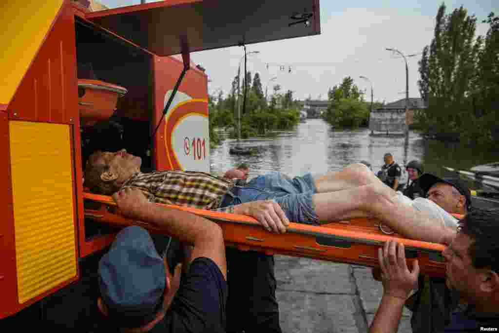 Rescuers evacuate a local resident from a flooded area after the Nova Kakhovka dam breached, amid Russia's attack on Ukraine, in Kherson, Ukraine, June 7, 2023.