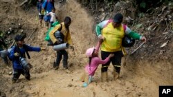 FILE - Seorang perempuan migran Ekuador mengangkat seorang anak dari jalan berlumpur saat berjalan melintasi Celah Darien dari Kolombia ke Panama dengan harapan bisa mencapai AS, 15 Oktober 2022. (AP/Fernando Vergara, File)