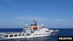 资料照:2024年2月8日,菲律宾南中国海斯卡伯勒浅滩附近,一艘中国海岸警卫队船只在菲律宾海岸警卫队船只特雷莎·马格巴努亚号旁驶过。(路透社)