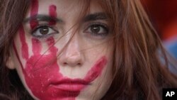 Seorang perempuan mengikuti unjuk rasa untuk memperingati Hari Penghapusan Kekerasan Terhadap Perempuan, di Milan, Italia, Sabtu, 25 November 2023. (Foto: Luca Bruno/AP Photo)