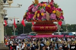 Pengunjung berkumpul di dekat keranjang bunga raksasa yang dipajang di Lapangan Tiananmen yang ramai untuk merayakan ulang tahun ke-74 berdirinya Republik Rakyat China, di Beijing, Kamis, 28 September 2023. (AP/Andy Wong)