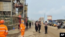 Sejumlah polisi dan pekerja berjaga di dekat lokasi ledakan tungku smelter di PT Indonesia Tsingshan Stainless Steel di Morowali, Sulawesi Tengah, pada 24 Desember 2023. (Foto: AP)