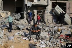 Warga Palestina bangunan-bangunan yang hancur akibat serangan Israel di Jalur Gaza di Rafah, Senin, 4 Desember 2023. (AP Photo/Hatem Ali)