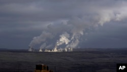 FILE - Steam rises from a power plant located by the Turow lignite coal mine near the town of Bogatynia, Poland, Jan. 15, 2022.