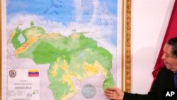 Chairman of the Special Commission for the Defense of Guyana Essequibo Hermann Escarra stands next to Venezuela's new map that includes the Essequibo territory in Caracas, Venezuela, Dec. 8, 2023.