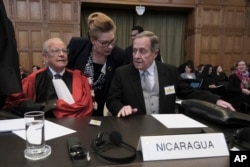 Duta Besar Nikaragua Carlos Jose Arguello Gomez (kanan), dan Alain Pellet (kiri), pengacara yang mewakili Nikaragua, menunggu dimulainya sidang dua hari di Pengadilan Dunia di Den Haag, Belanda, Senin, 8 April 2024. (AP/Postingan Patrick)