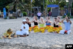 Sejumlah turis mancanegara mengikuti upacara ritual Hindu di pantai di kawasan Seminyak, Bali, 5 Agustus 2023. (Foto: Sonny Tumbelaka/AFP)