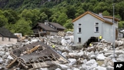 Petugas penyelamat memeriksa lokasi tanah longsor akibat cuaca buruk dan hujan lebat di lembah Misox, di Desa Sorte, Lostallo, Swiss selatan pada Minggu 23 Juni 2024. (Foto: via AP)