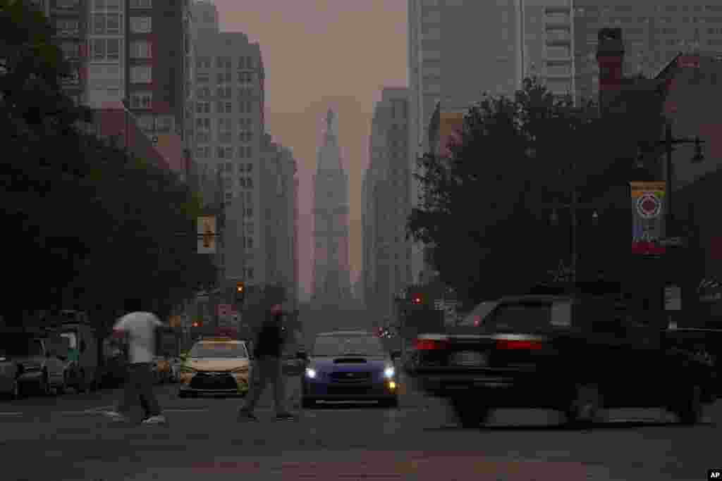 Evening commuters travel on Broad Street past a hazy City Hall, June 7, 2023, in Philadelphia, Pennsylvania. Smoke from Canadian wildfires poured into the U.S. East Coast and Midwest on Wednesday, covering the capitals of both nations in an unhealthy haze, and prompting people to fish out pandemic-era face masks.