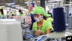 FILE - In this Oct. 24, 2017, photo, a worker sews a garment at Pro Sports factory in Nam Dinh province, Vietnam.