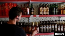 Seorang pemilik toko miras memeriksa botol-botol minuman beralkohol di tokonya di Qaraqosh, selatan Mosul, Irak, 18 Juli 2017. (REUTERS/Thaier Al-Sudani)