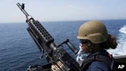 US Navy retail service specialist Artayja Stewart of Clarksville, Tenn., stands guard next to a machine gun aboard the USS Paul Hamilton in the Strait of Hormuz, May 19, 2023. 