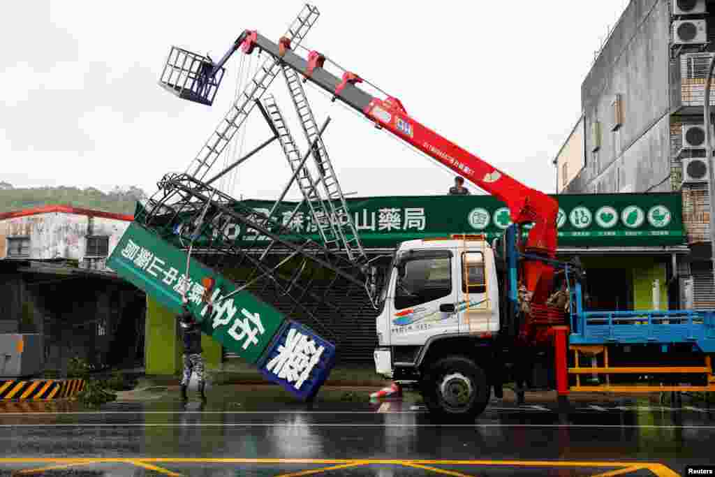 Workers use a crane to remove a fallen sign after Typhoon Gaemi passed northern Taiwan in Yilan, Taiwan, July 25, 2024.