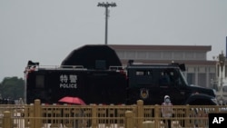Žena stoji blizu policijskog vozila na trgu Tjenanment u Pekingu, 4. juna 2024. 