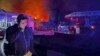 The Governor of Sevastopol, Mikhail Razvozhaev, is seen speaking on a phone as smoke and flame rise from a burning shipyard in Crimea in this photo posted to Razvozhaev's Telegram channel on Sept. 13, 2023.