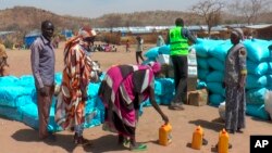 FILE - Sudanese refugees displaced by the conflict in Sudan gather to receive food staples from aid agencies at the Metche Camp in eastern Chad, March 5, 2024. 