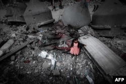 Seorang gadis Palestina mengenakan gaun merah muda berdiri di tengah reruntuhan Masjid Al-Faruq yang hancur akibat pengeboman Israel, di Rafah di Jalur Gaza selatan. (Foto: AFP)