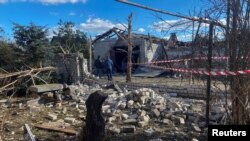 Pria lokal berdiri di samping bangunan tempat tinggal yang rusak akibat serangan rudal Rusia, di tengah serangan Rusia ke Ukraina, di desa Obukhivka, wilayah Dnipropetrovsk, Ukraina 18 Oktober 2023. (REUTERS/Mykola Synelnykov)