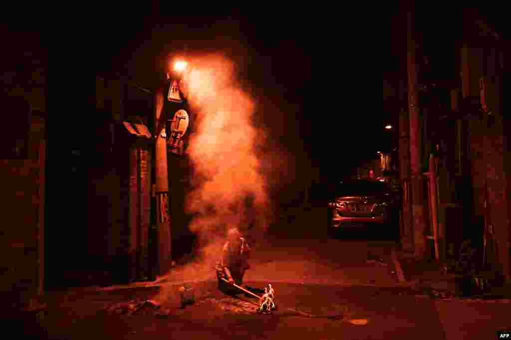 A woman burns offerings for her dead ancestors on a street during the Hungry Ghost Festival in Beijing, China, Aug. 18, 2024.