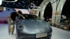 Seorang karyawan sedang membersihkan mobil listrik Ora di sebuah pameran di Shanghai, China, 18 April 2023. (Foto: Ng Han Guan/AP Photo)