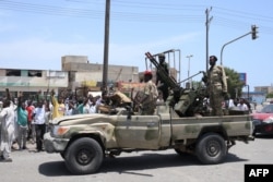 Warga Sudan menyapa tentara, yang setia kepada panglima militer Abdel Fattah al-Burhan, di kota Laut Merah Port Sudan pada 16 April 2023. (Foto: AFP)