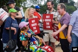 FILE - Protesters hold signs that say 'Not Above the Law' as they gather on Aug. 3, 2023, in Washington.