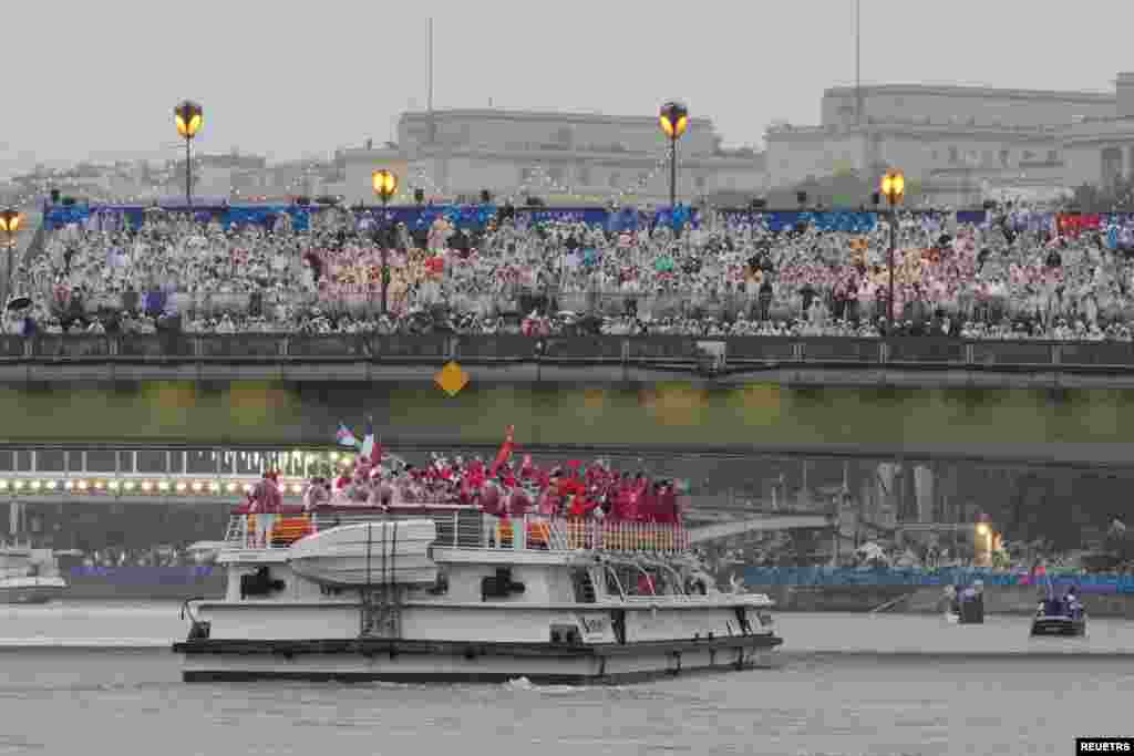 China's and Canada's teams move down the Seine as spectators look on in the rain in Paris during the opening ceremony of the 2024 Summer Olympics, July 26, 2024.