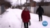 A woman walks through snow in Nova Kozacha, Ukraine, Feb. 14, 2023. The small border village of Nova Kozacha lost more than 75% of its population since the beginning of the war. Few people are back, and many fear Russia will attack again. 