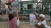Dos mujeres cuelgan carteles anunciando las elecciones legislativas en La Habana, Cuba, 25 de marzo de 2023. REUTERS/Alexandre Meneghini
