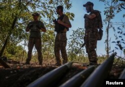 Tiga prajurit Ukraina berdiri di dekat peluru artileri di garis depan, di tengah serangan Rusia terhadap Ukraina, di wilayah Donetsk, Ukraina, Jumat 22 September 2023.