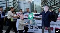 资料照片：韩国首尔的抗议者戴着印有日本首相岸田文雄和韩国总统尹锡悦头像的面罩，手拿着显示Line应用程序的标牌。（2024年5月14日）