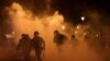 FILE - French CRS riot police run amid clashes with protesters during a demonstration as part of the ninth day of nationwide strikes and protests against French government's pension reform, in Paris, March 23, 2023. 