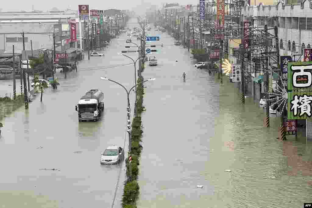 People and vehicles wade through the water along a street that was flooded by Typhoon Gaemi in Kaohsiung, Taiwan, July 25, 2024. The typhoon -- the strongest to hit Taiwan in eight years -- had already forced authorities on the island to close schools and offices, suspend the stock market and evacuate thousands of people.