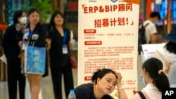 資料照片：2023年6月9日，一名招聘人員在北京一家購物中心招聘會的展位上與申請人交談。 （美聯社照片）