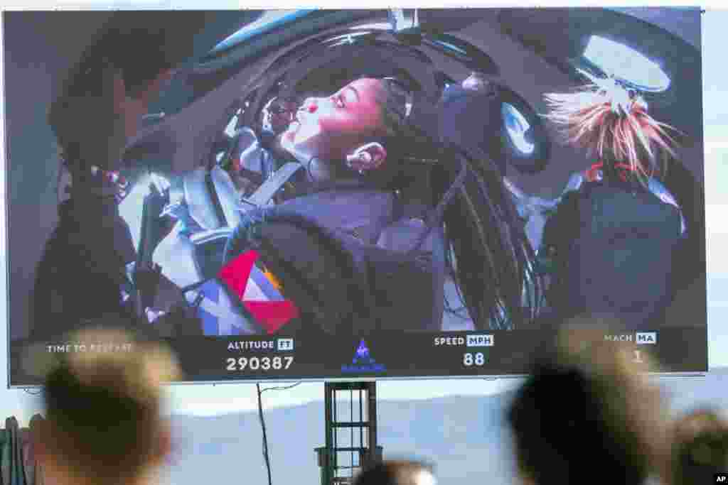 Guests watch a live broadcast from inside Virgin Galactic's rocket-powered plane Unity 22, showing space tourists Anastatia Mayers, 18, and her mother Keisha Schahaff, rear, at Spaceport America, near Truth or Consequences, New Mexico. 