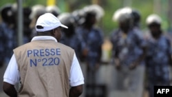 Foto ilustrasi yang menunjukkan seorang jurnalis melihat ke arah pasukan kemananan yang berjaga dalam sebuah aksi protes di Lome, Togo, pada 19 Februari 2013. (Foto: AFP/Daniel Hayduk)