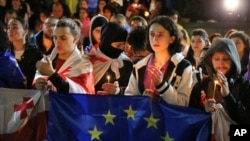 Demonstrators with Georgian and EU flags and candles stand in front of the Kashveti Church of St. George during an opposition protest against a draft "foreign agents" bill in the center of Tbilisi, Georgia, May 3, 2024.