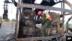In this photo released by the Rescue 1122 Emergency Department, rescue workers examine a burnt bus in Pindi Bhattian, Pakistan, Aug. 20, 2023.