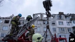 Rescue workers climb by ladder as they clear the rubble of the residential building which was destroyed by a Russian rocket in Pokrovsk, Ukraine, Feb. 15, 2023. 