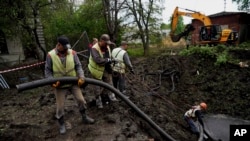 Municipal workers pump water from a crater after a Russian attack on mental hospital №3 in Kharkiv, Ukraine, April 27, 2024. Russian drones early Sunday also struck the Black Sea city of Mykolaiv. 